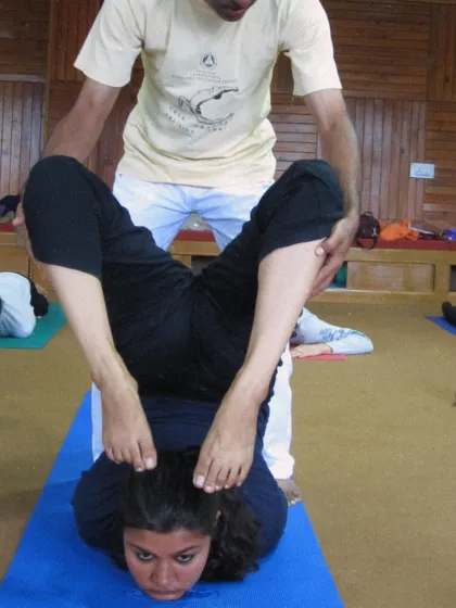 A student receives assistance in a deep flexibility posture during a past TTC. This shows our commitment to helping each student explore their potential safely.