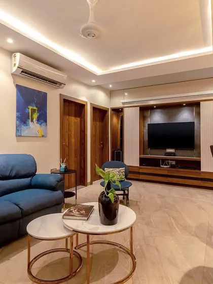 An informal living or family room featuring comfortable blue leather sofas and a modern media unit. This space is designed for movie nights and casual relaxation.