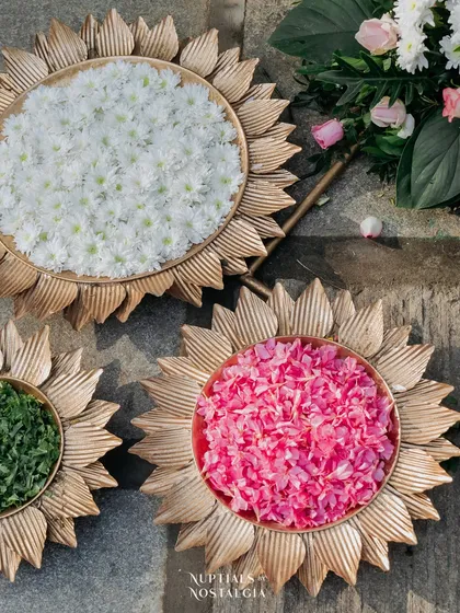 Golden platters holding colorful flower petals, ready for guests to shower the couple with blessings.