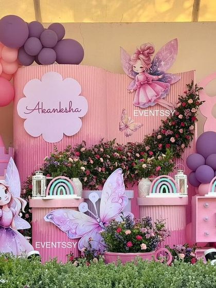 Another view of the fairy theme party, showcasing the storybook-style backdrop and a large marquee number "5." The combination of pink and purple hues creates a soft and dreamy atmosphere.