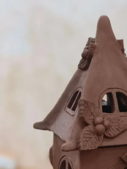 A close-up of the delicate details on a clay house lantern. Students learn to carve windows and add small decorative elements like leaves and berries to make their creations unique.
