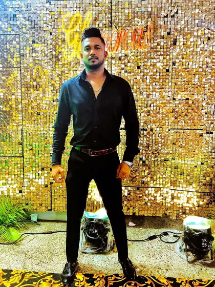 A full-length shot against a glittering gold backdrop. I fit perfectly into the glamorous setting of a modern Indian wedding reception.