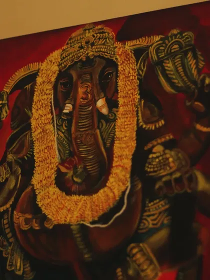 An angled shot that captures the depth and rich colors of the Ganesha painting, especially the contrast between the red background and the dark idol.