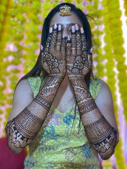 A full view of the bride's hands, covered in a dense and intricate traditional mehandi pattern.