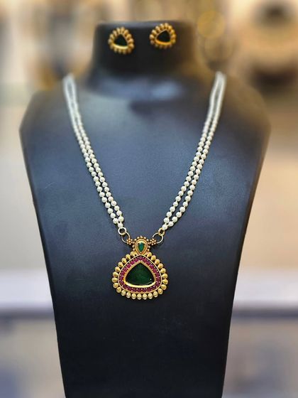 A minimal and elegant necklace with a double pearl chain and a green stone pendant.