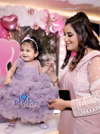 A mother holds her daughter's hand as she takes a few steps. These small, tender interactions make for some of the most precious photographs from a first birthday shoot.