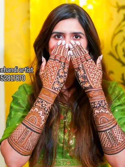 A happy bride showcasing her intricate jaali (net) pattern mehndi. This design covers the full hands and arms for a complete bridal look.