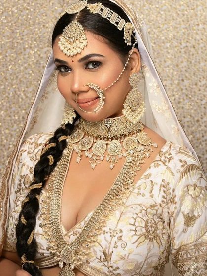 An elegant bride in an all-white lehenga, adorned with a matching white and gold coin-style necklace set. A unique and regal choice.
