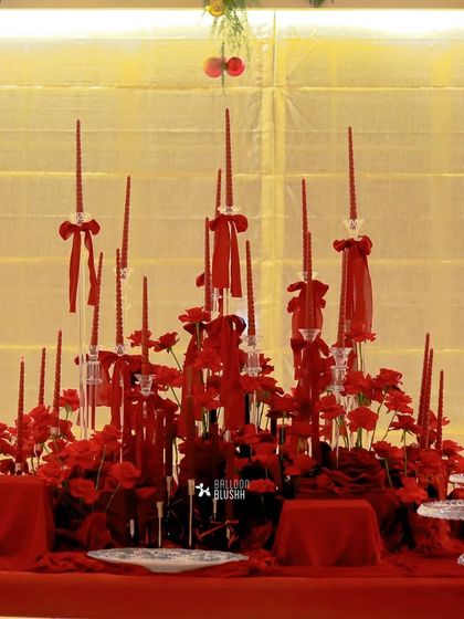 A dramatic tablescape of red flowers and dozens of tall, red taper candles, creating a bold and romantic holiday statement.