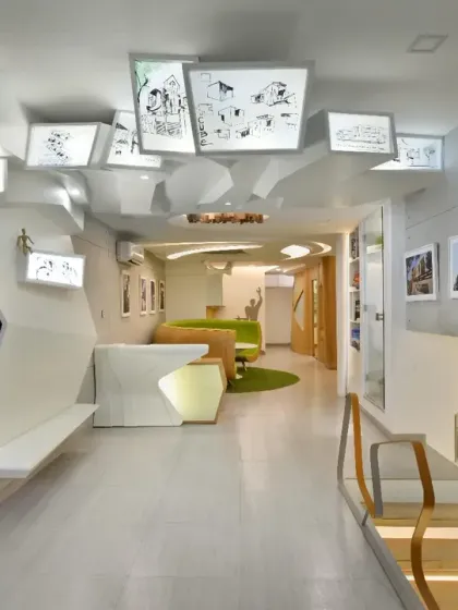 The front office of my studio, where cement-textured walls create a neutral gallery-like backdrop for display panels. An abstract white partition defines the waiting area and continues onto the ceiling, reflecting our firm's design ideology.