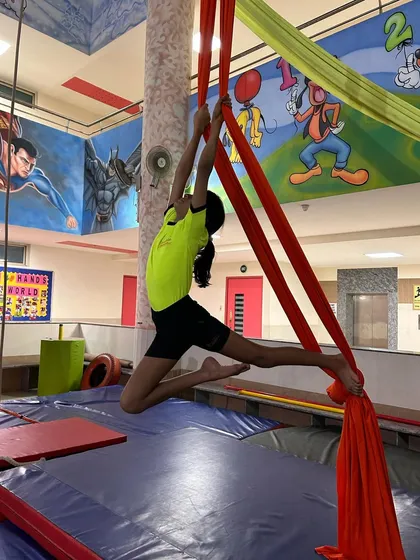 A young student reaches high, practicing a climbing pose that builds upper body strength and technique.