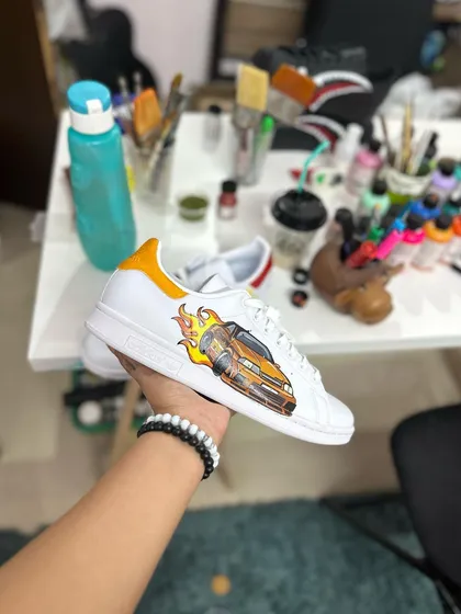 A custom Adidas Stan Smith with a flaming car, painted live at the store event.
