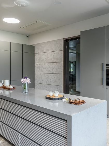 A full view of the handle-less, floor-to-ceiling pantry cabinets, which provide extensive storage and contribute to the kitchen's clean, uncluttered aesthetic.