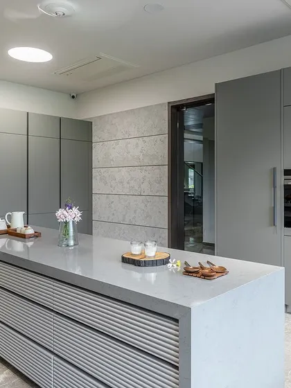 A full view of the handle-less, floor-to-ceiling pantry cabinets, which provide extensive storage and contribute to the kitchen's clean, uncluttered aesthetic.