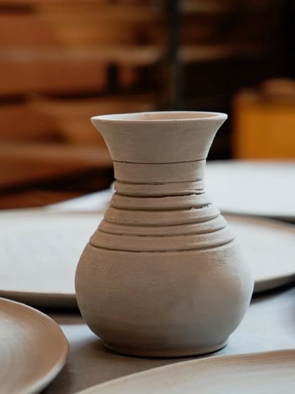 A close-up of a freshly thrown vase, with the throwing lines still visible, showcasing the beauty of the raw, unfired clay.