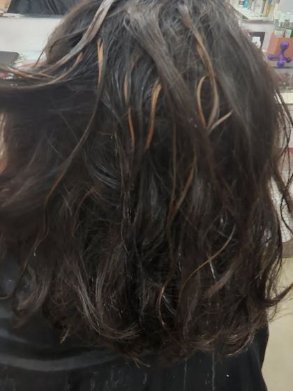 This image shows the "during" phase of a highlight service. The fine strands of hair are carefully selected to create a natural and blended effect once the colour is applied.