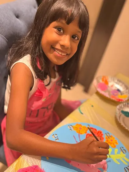A young artist focused on adding the finishing touches to her flamingo clock at a birthday paint party. I provide pre sketched canvases so kids can focus on the joy of painting.