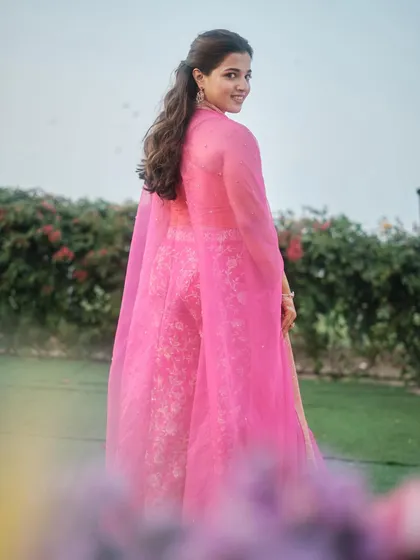 A beautiful shot of the bride in her vibrant pink outfit. The makeup is minimal and fresh, allowing her natural beauty and the stunning color of her lehenga to shine.