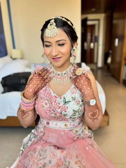 A close-up on the soft pink tones of the makeup, which perfectly match the floral embroidery on the lehenga.