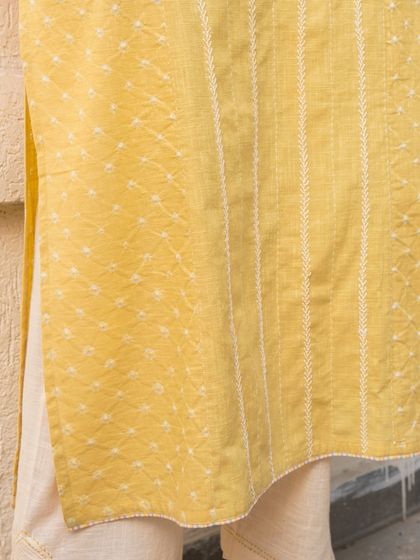 A close-up of the fabric and embroidery on our yellow Suhani A-Line Kurta. The combination of hand-tied Bandhani and fine stitch work creates a textured, visually interesting piece that celebrates craft.