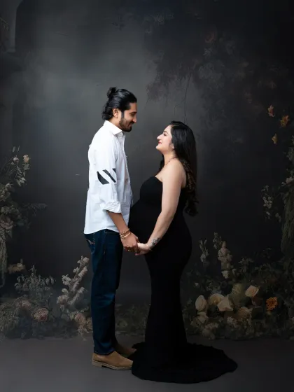 A classic couple's pose against a moody, floral backdrop. Their matching dark outfits create a sophisticated and cohesive look.