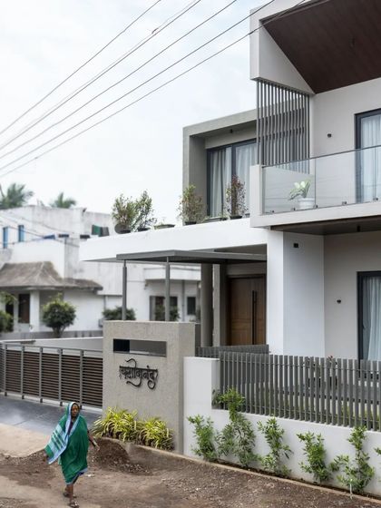 The 'Yashodanand' home presents a modern facade to the street, with clean lines, cantilevered volumes, and a subtle color palette.