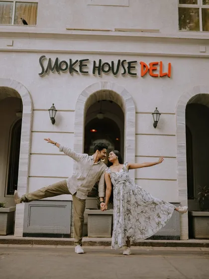 A fun and energetic pose in front of a classic Mumbai landmark, Smoke House Deli. This shot perfectly captures the couple's joyful and carefree spirit.
