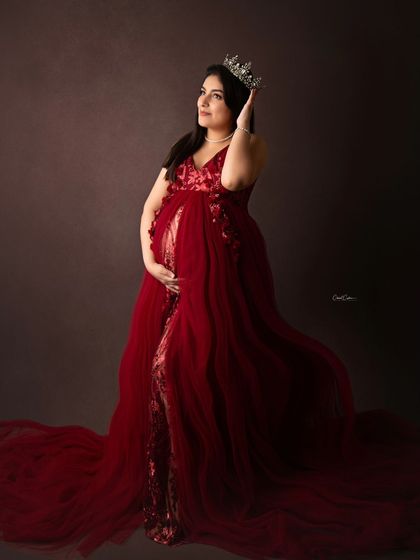 Every mother is a queen. This portrait features a mom-to-be in a regal red gown, complete with a sparkling crown, looking powerful and beautiful.