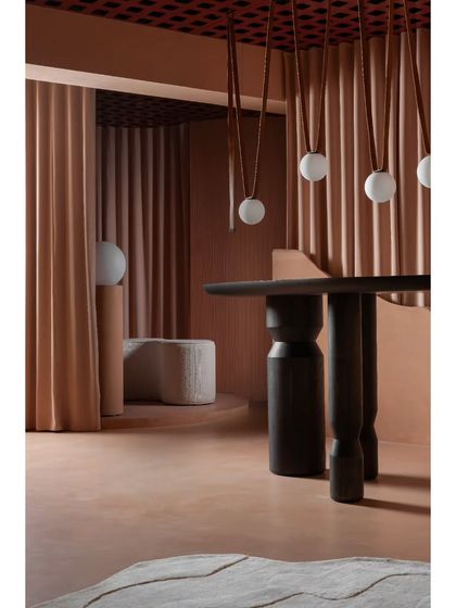 A closer look at the interplay of textures. The smooth micro-topping floor, the fluted wall panels, and the dark, sculptural table create a rich tactile experience that complements the hanging globe lights.