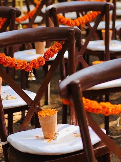 A close up of the guest seating arrangement. We used traditional wooden chairs adorned with simple marigold garlands, creating a look that is both rustic and elegant.