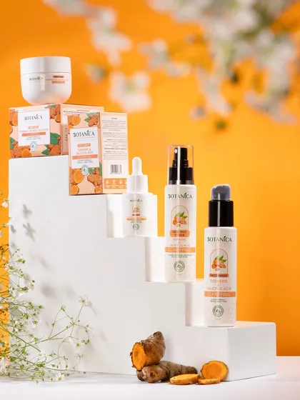 A full range of turmeric-based skincare products arranged on white steps. This "product family" shot effectively showcases the entire collection against a vibrant, color-coordinated background.