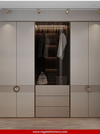This elegant wardrobe features fluted details and chic circular handles. The central glass display with interior lighting is perfect for showcasing handbags or other prized accessories.
