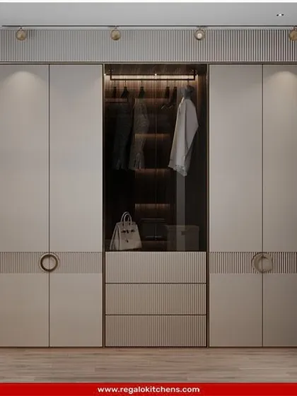 This elegant wardrobe features fluted details and chic circular handles. The central glass display with interior lighting is perfect for showcasing handbags or other prized accessories.