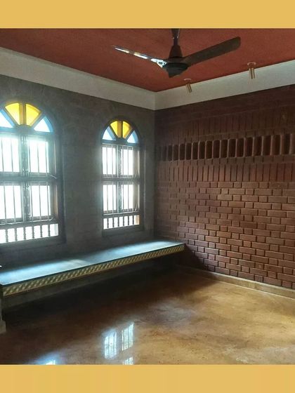 A cozy room with a built-in window seat, arched windows with colored glass, and exposed brick walls.