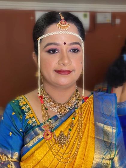 Bride Swathi's Muhurtham look, featuring a traditional Maharashtrian-style nose ring and layered gold jewellery, paired with a classic yellow silk saree.