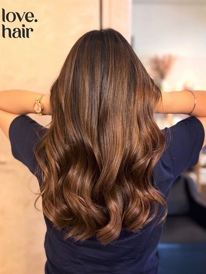 The back view of our pure hazelnut balayage, showing off the long, healthy waves and the beautiful blend of colour.