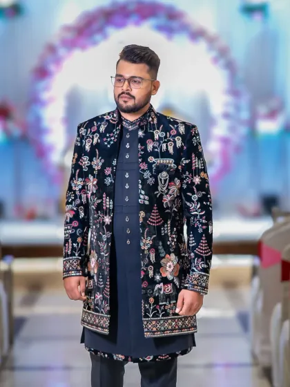 A stylish portrait of the groom-to-be at his engagement party. His intricately embroidered sherwani looks incredible against the festive backdrop.
