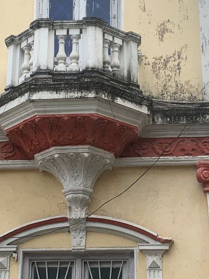 A detailed shot of a balcony on the Art Deco palace, showcasing the blend of classical balusters with stylized, decorative corbels below.