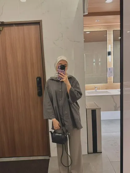 A customer's mirror selfie showing her styling the black Metro Mini bag. It's the perfect size for a minimalist look while still being practical.
