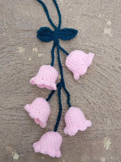 A pink bell-flower car hanging, perfect for adding a delicate touch to your car's interior.