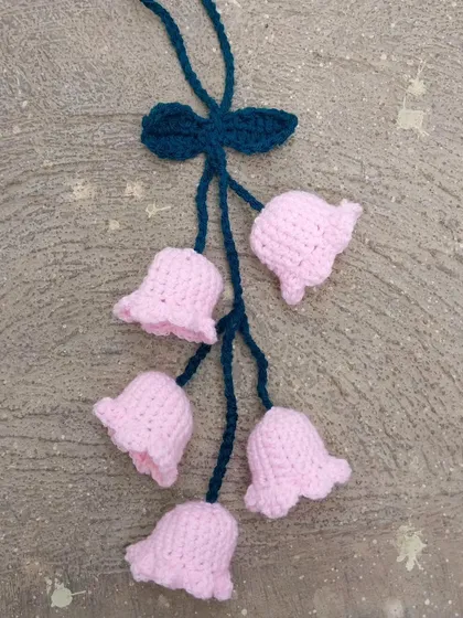 A pink bell-flower car hanging, perfect for adding a delicate touch to your car's interior.