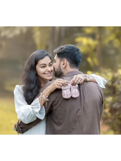 This is the moment it all becomes real. Here, the expecting mother shares a happy, knowing smile with her partner while holding up a tiny pair of baby shoes, a beautiful symbol of the little one they are eagerly awaiting.