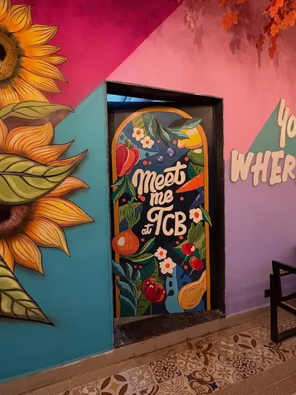 The kitchen door art, the sunflower mural, and the motivational quote wall all in one frame, demonstrating a complete artistic vision for the cafe.