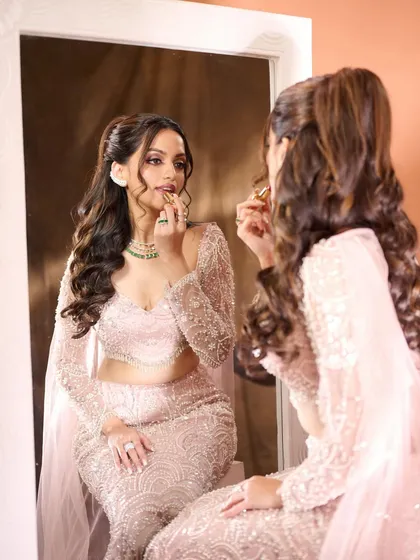 The final touch. This shot captures the bride applying her lipstick, a moment that symbolizes the completion of her stunning transformation. The makeup is flawless, ready for a night of celebration.