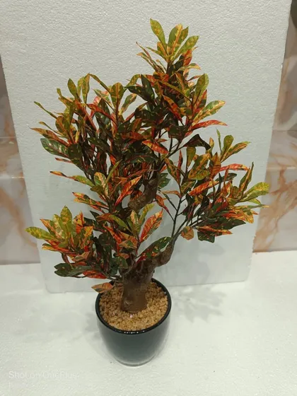 A vibrant artificial Croton plant with red, orange, and green leaves, providing a warm and colorful accent.