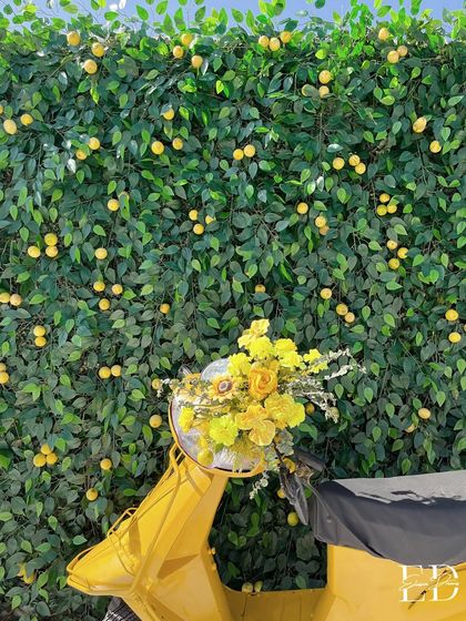 A bright yellow scooter, its basket overflowing with yellow flowers, parked in front of a lemon-tree wall. This playful prop served as a charming photo opportunity for guests.