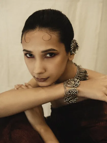 A close-up that highlights the beautiful silver jewelry and the soft, modern take on traditional makeup. The model's pose is gentle and introspective.