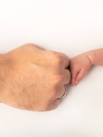 A baby's tiny hand reaching out to a parent's fist. This symbolic shot represents the powerful connection and bond within a family.