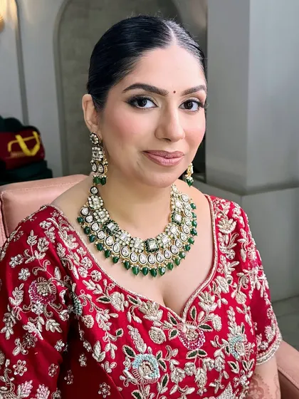 A full view of the bride's classic makeup look. Her skin is radiant, her eyes are beautifully defined, and the entire look comes together with her traditional attire and jewelry.
