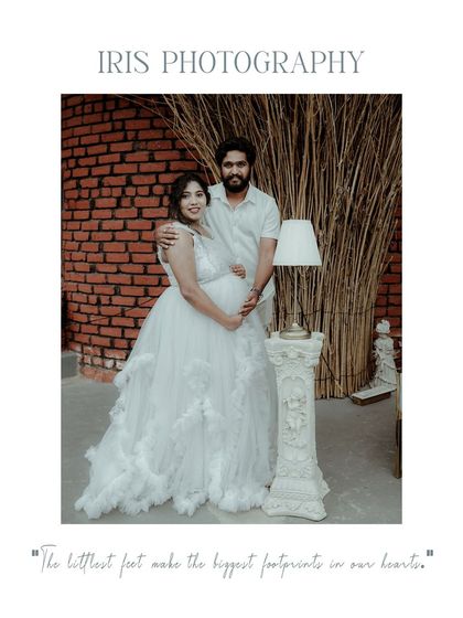 A studio maternity portrait of a couple in white, standing next to a decorative pillar and lamp. This image has a classic, posed feel, perfect for a timeless keepsake.
